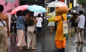 '우산은 거들 뿐'... 비오는 거리 홍보하는 인형탈 알바생